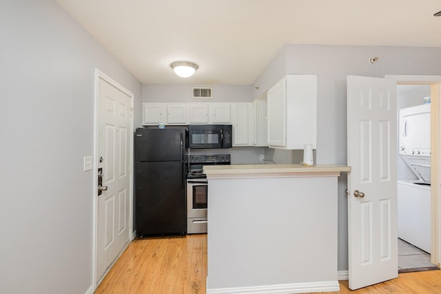 kitchen featuring kitchen peninsula, stacked washer and dryer, light hardwood / wood-style floors, white cabinets, and black appliances