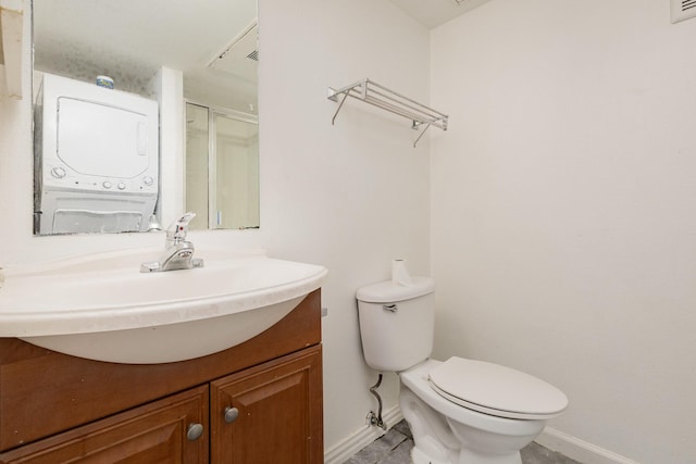 bathroom with vanity, stacked washer and dryer, toilet, and walk in shower