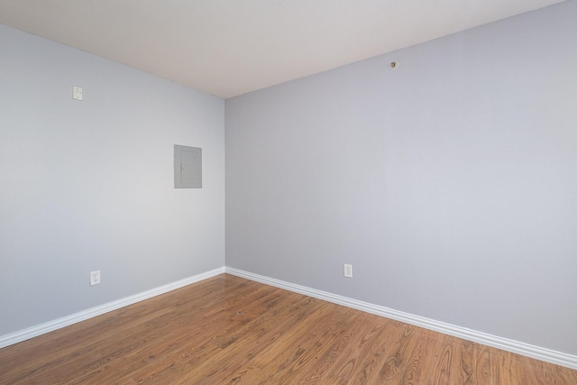 unfurnished room featuring electric panel and hardwood / wood-style flooring