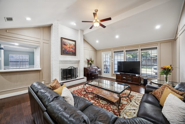 living room featuring dark wood-type flooring, ceiling fan, lofted ceiling, and a brick fireplace