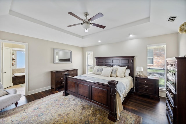 bedroom featuring ensuite bathroom, dark hardwood / wood-style floors, and a raised ceiling