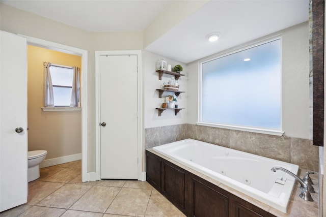 bathroom with a tub to relax in, tile patterned floors, and toilet