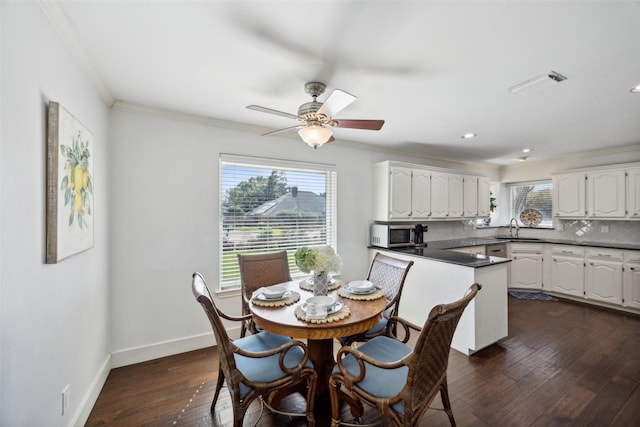 dining space featuring sink, crown molding, dark wood-type flooring, and ceiling fan