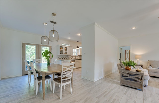 dining room with crown molding and light hardwood / wood-style flooring