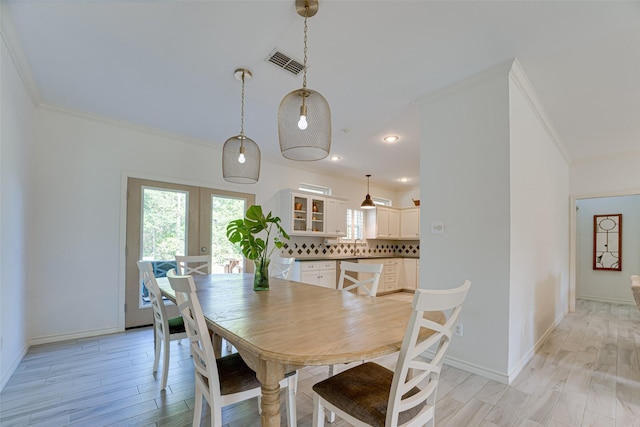 dining room with crown molding, french doors, and light hardwood / wood-style flooring