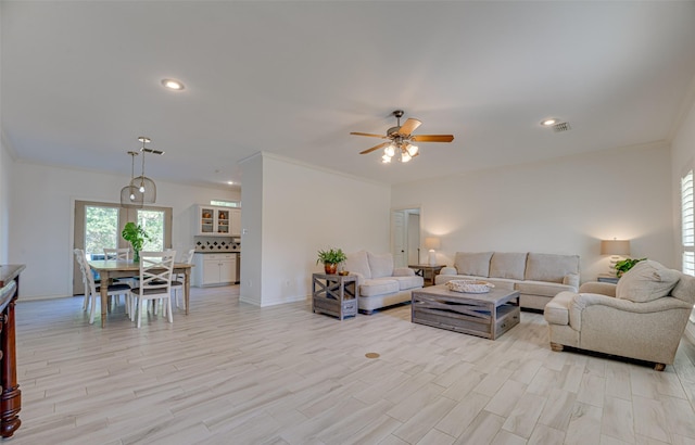 living room with light wood-type flooring, ceiling fan, and crown molding