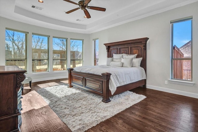 bedroom featuring ornamental molding, a tray ceiling, ceiling fan, and dark wood-type flooring