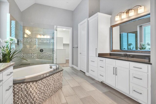 bathroom featuring vanity, vaulted ceiling, and shower with separate bathtub