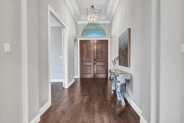 foyer entrance with a high ceiling, dark hardwood / wood-style flooring, an inviting chandelier, and crown molding