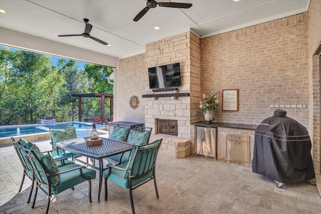 view of patio / terrace featuring an outdoor stone fireplace, area for grilling, ceiling fan, and an outdoor kitchen