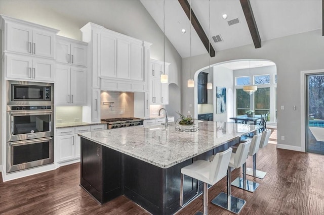 kitchen with beam ceiling, white cabinetry, a large island, hanging light fixtures, and backsplash