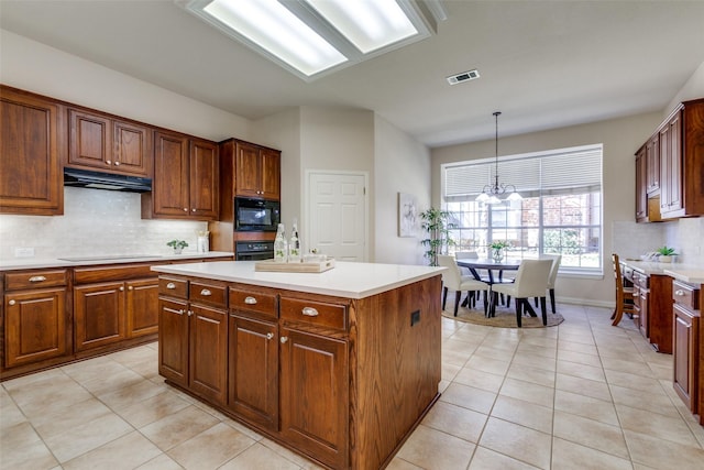 kitchen featuring light tile patterned floors, hanging light fixtures, a center island, tasteful backsplash, and black appliances