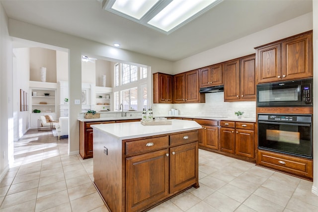 kitchen with light tile patterned flooring, sink, black appliances, a center island, and backsplash