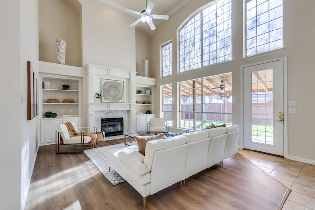 living room featuring ceiling fan, a towering ceiling, and a high end fireplace