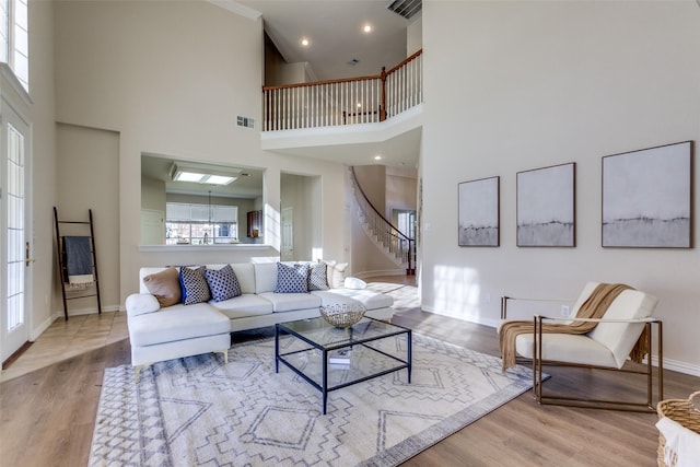 living room with a towering ceiling and light hardwood / wood-style flooring