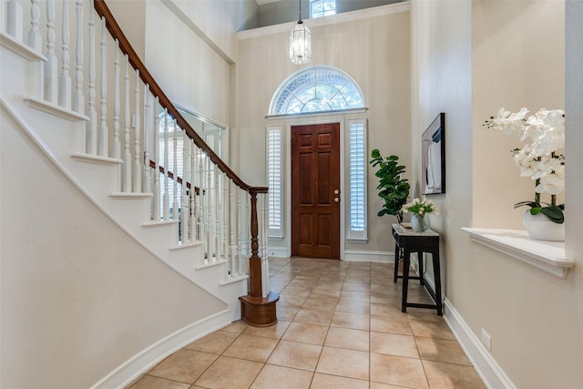 tiled entryway with a high ceiling and a notable chandelier