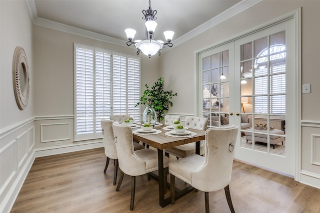 dining area featuring an inviting chandelier, crown molding, wood-type flooring, and french doors