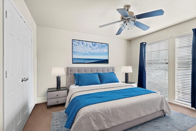 carpeted bedroom with ceiling fan, baseboards, and a closet