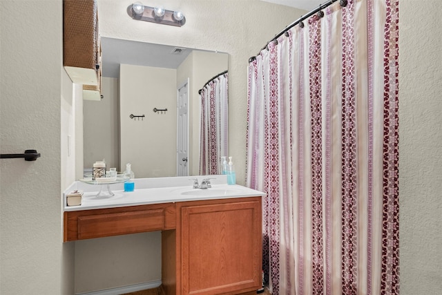 bathroom with visible vents, a textured wall, and vanity