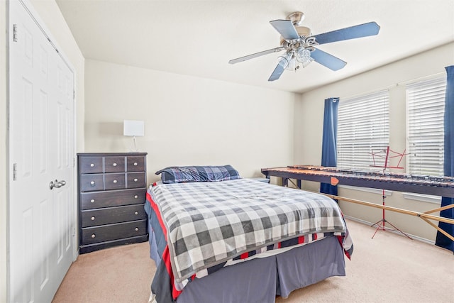 carpeted bedroom featuring ceiling fan and a closet