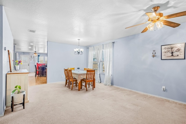 dining room featuring visible vents, light carpet, a textured ceiling, baseboards, and ceiling fan with notable chandelier