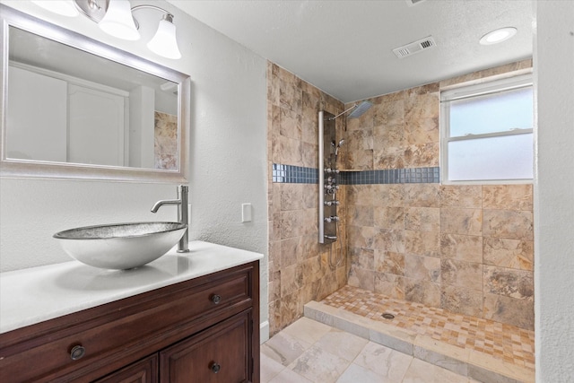 bathroom with vanity and a tile shower