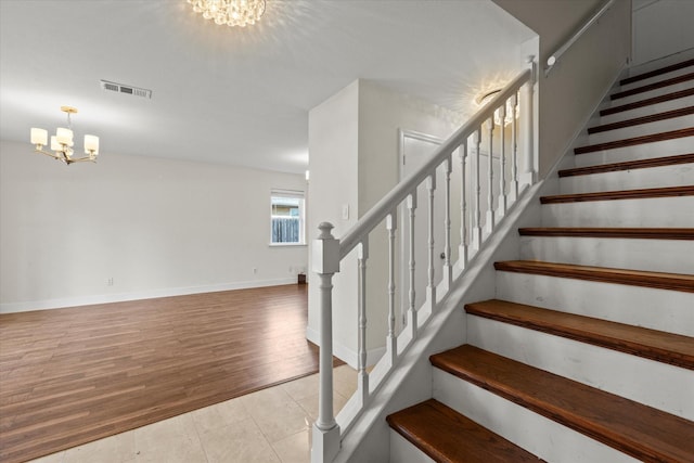 staircase with wood-type flooring and a chandelier