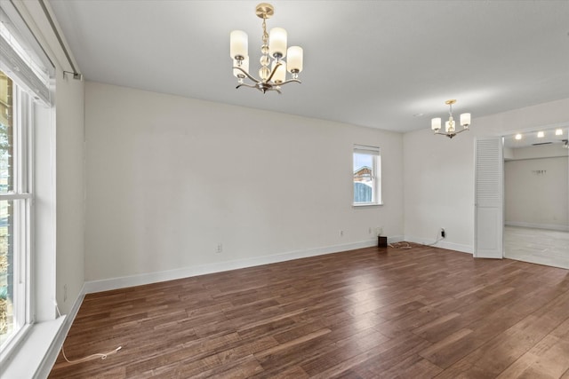 unfurnished room featuring an inviting chandelier and dark hardwood / wood-style floors