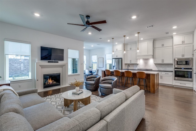 living room featuring ceiling fan, dark hardwood / wood-style flooring, and sink