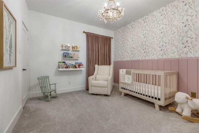 carpeted bedroom featuring an inviting chandelier and a nursery area