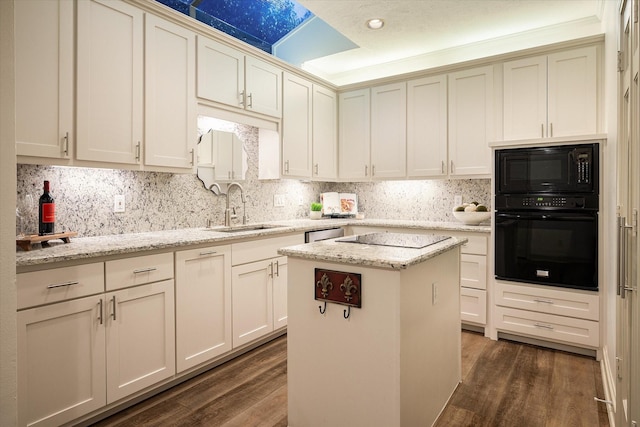 kitchen with a sink, black appliances, light stone counters, and a kitchen island