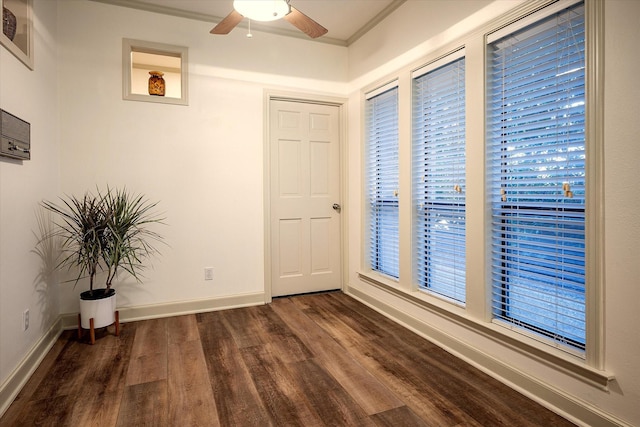 unfurnished room with dark wood-type flooring, ornamental molding, baseboards, and a ceiling fan