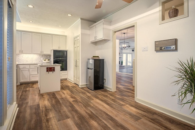 kitchen featuring decorative backsplash, black appliances, white cabinets, dark hardwood / wood-style floors, and a kitchen island