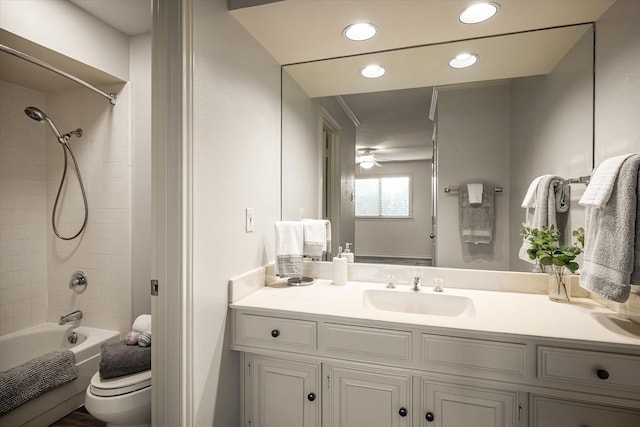 full bathroom with vanity, tiled shower / bath combo, toilet, and ceiling fan