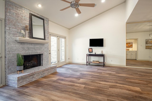 unfurnished living room with ceiling fan, high vaulted ceiling, crown molding, a fireplace, and hardwood / wood-style flooring