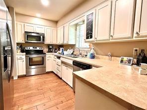 kitchen with white cabinets, light hardwood / wood-style floors, sink, and stainless steel appliances