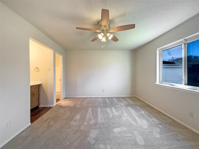 unfurnished bedroom featuring a textured ceiling, ceiling fan, light carpet, and connected bathroom