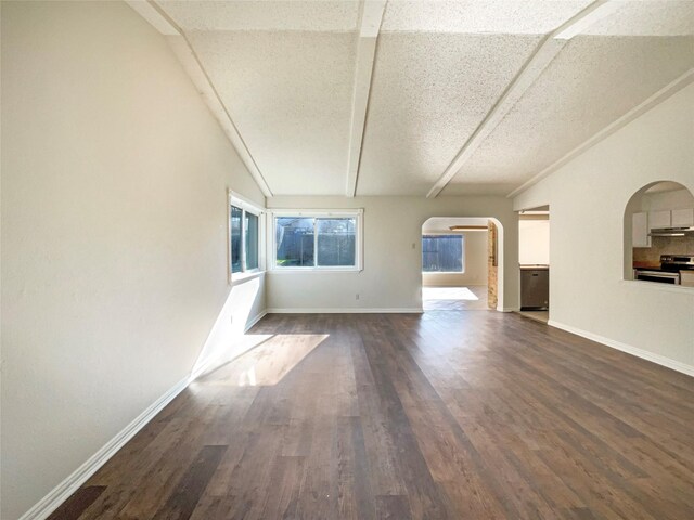 unfurnished living room with dark hardwood / wood-style flooring, a textured ceiling, vaulted ceiling, and a wealth of natural light