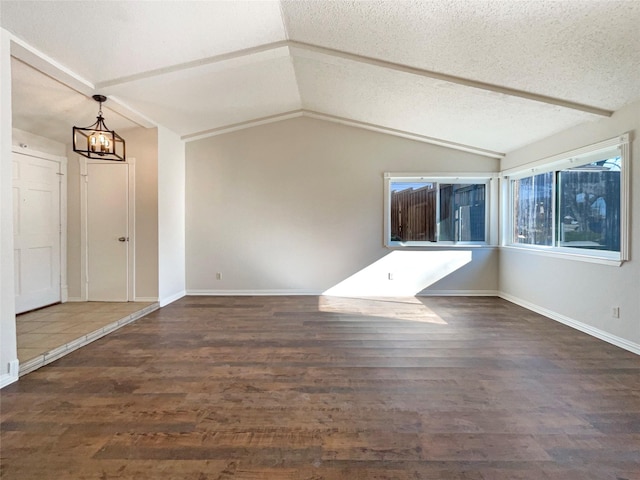 interior space with dark wood-type flooring, lofted ceiling, an inviting chandelier, and a textured ceiling