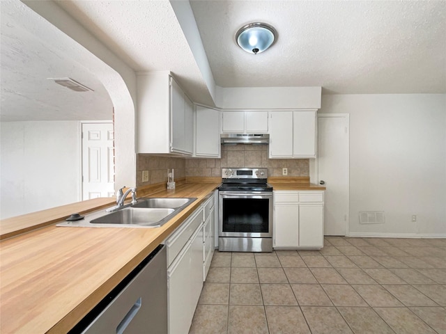 kitchen featuring decorative backsplash, stainless steel appliances, sink, light tile patterned floors, and white cabinets