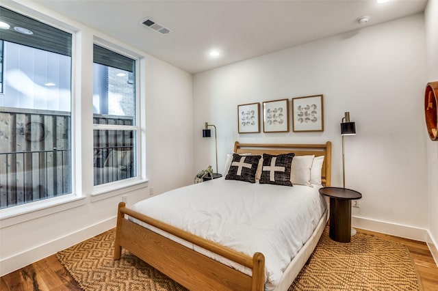 bedroom with recessed lighting, wood finished floors, visible vents, and baseboards