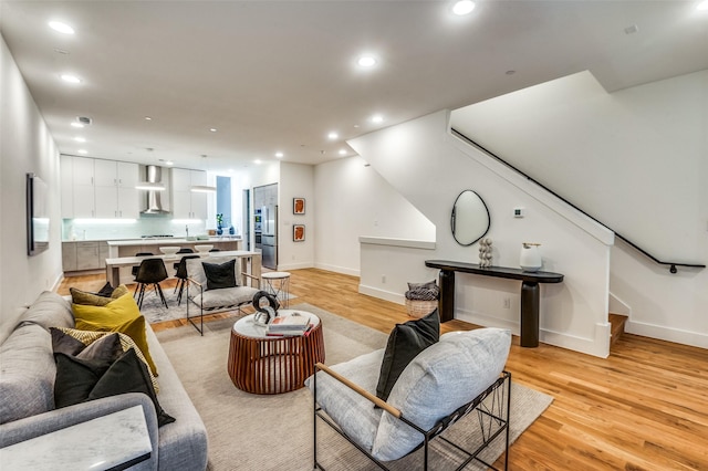 living room with recessed lighting, light wood-style flooring, baseboards, and stairs