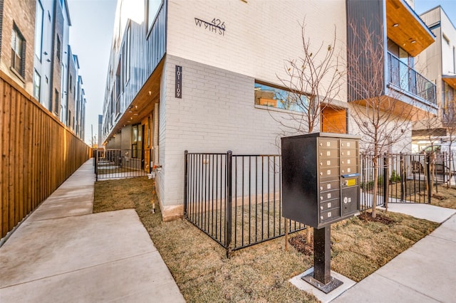 exterior space with mail area, fence, and brick siding