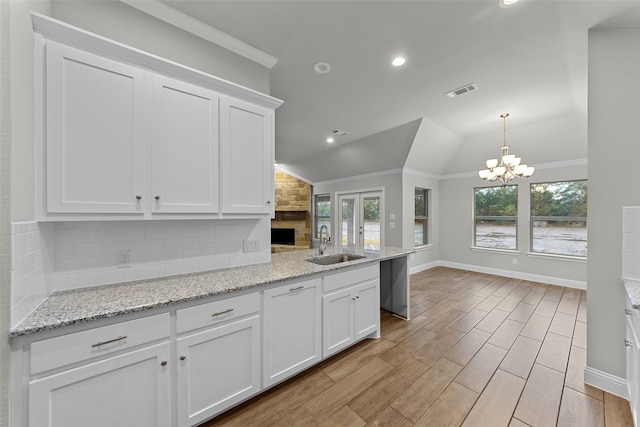 kitchen with decorative backsplash, white cabinetry, lofted ceiling, and sink