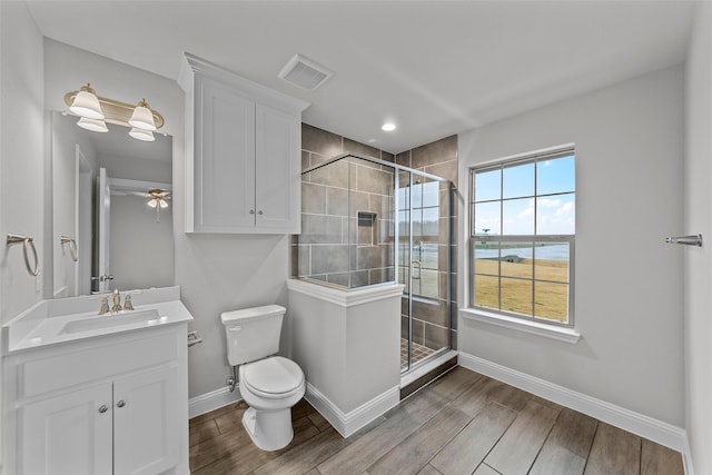 bathroom featuring vanity, ceiling fan, toilet, and a shower with door