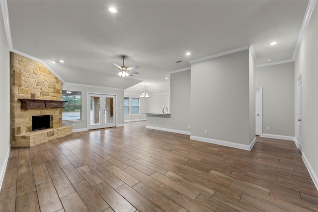 unfurnished living room with ceiling fan with notable chandelier, a stone fireplace, sink, vaulted ceiling, and ornamental molding