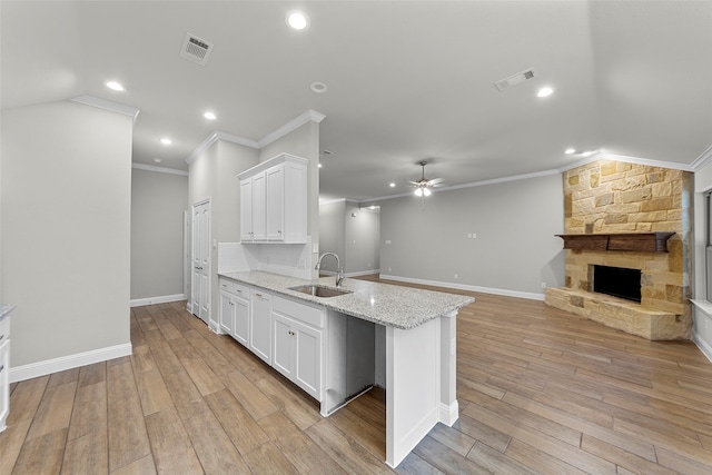 kitchen featuring white cabinets, ceiling fan, kitchen peninsula, and a fireplace