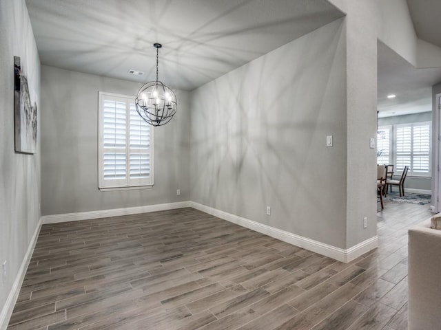 empty room featuring a chandelier and hardwood / wood-style flooring