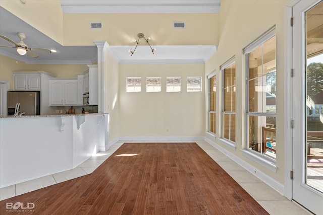 interior space with light tile patterned flooring, ceiling fan with notable chandelier, plenty of natural light, and ornamental molding