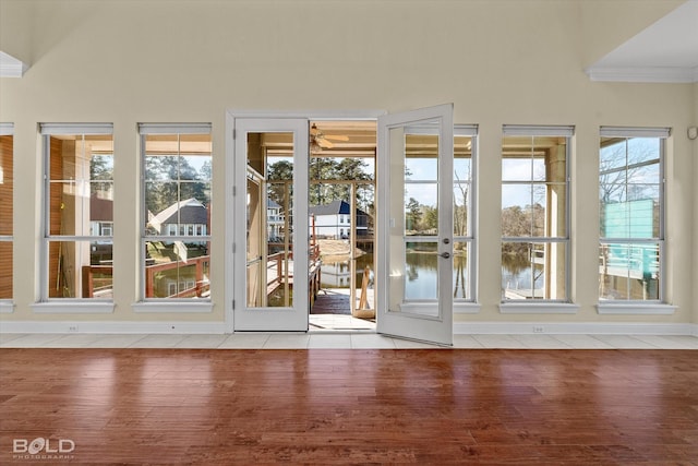 doorway featuring a water view, a healthy amount of sunlight, french doors, and light hardwood / wood-style flooring